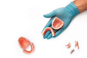 Gloved hand and collection of dental prostheses