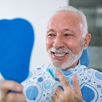 Man looking at smile after replacing a lost dental crown
