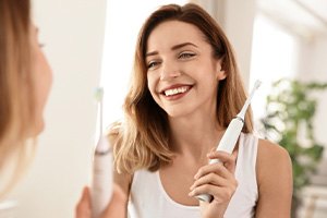 Woman brushing her teeth in front of bathroom mirror