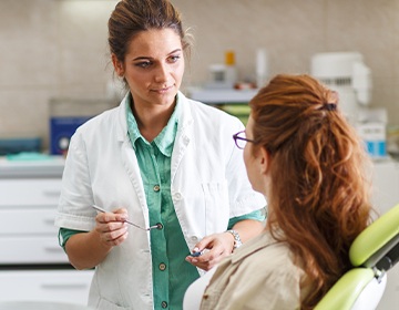 Dentist talking to redheaded woman in dental chair