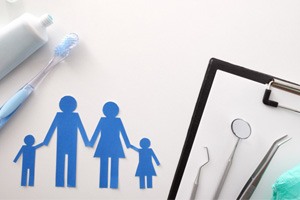 Paper cutouts of family next to dental instruments