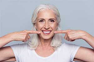 Woman pointing to smile after dental implant tooth replacement