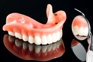 Implant dentures on dark reflective surface, next to mirror