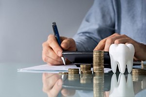 Man using calculator and pen to budget for dental care