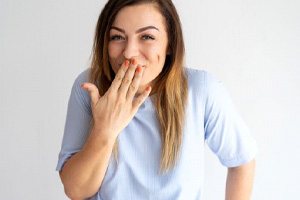 Smiling woman using hand to cover her mouth