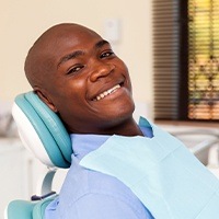 Man in dental chair smiling after treatment for a chipped or broken tooth