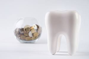 Tooth model sitting in front of jar of coins