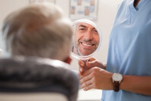 Happy patient admiring the results of his full mouth reconstruction