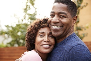 Man and woman with dental implant supported replacement teeth smiling