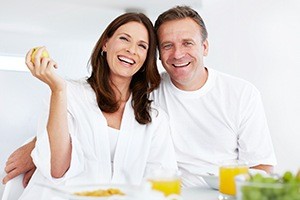 Man and woman smiling together after dental implant tooth replacement