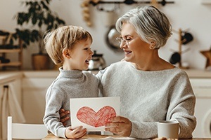 Grandmother smiling at grandchild after dental implant supported tooth replacement