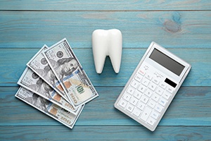 Money, tooth model, and calculator arranged on tabletop