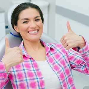 Happy dental patient making double thumbs-up gesture