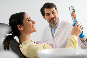 Dental patient looking at her smile in hand mirror