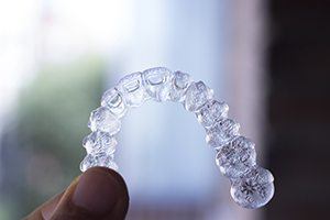 Patient holding up Invisalign clear braces tray