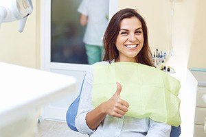 Smiling woman giving thumbs up during dental checkup and teeth cleaning visit