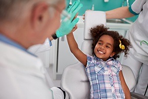 Little girl giving dentist high five during children's dentistry visit