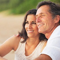 Man and woman smiling after dental implant tooth replacement