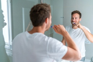 Man brushing teeth to maintain his white smile