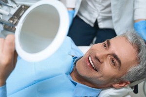 Dental patient holding mirror, admiring his new look