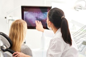 Patient and dentist looking at X-ray on monitor