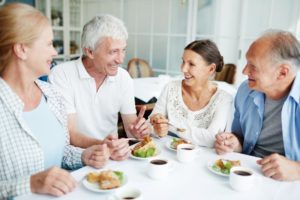 Happy group of senior friends eating with dentures