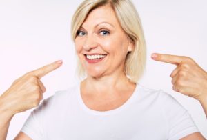 Happy senior woman pointing at her implant dentures