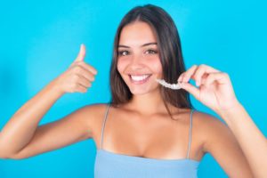 Woman holding Invisalign, making thumbs up gesture