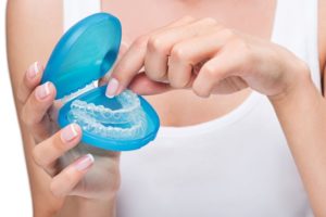 Woman taking clear aligner out of its storage case