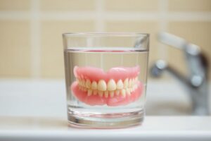 Dentures sitting in glass of water on bathroom counter 