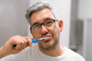 Gray-haired man brushing his teeth